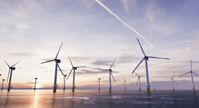 wind turbines in front of a cloudy grey-purple sky.